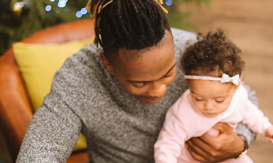 Dad, smiling with baby girl sat on lap