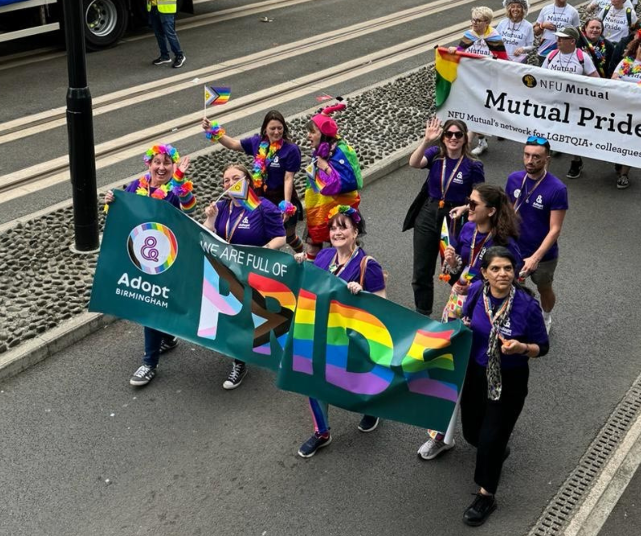 Group of people walking and smiling as a group in a parade with a large banner