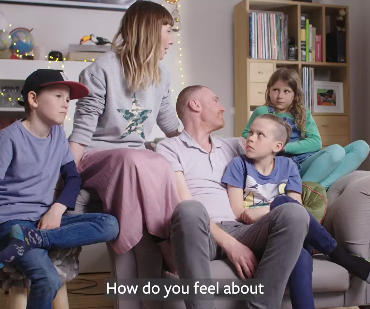 Mum and Dad sat on an armchair, surrounded by their 3 children in their home